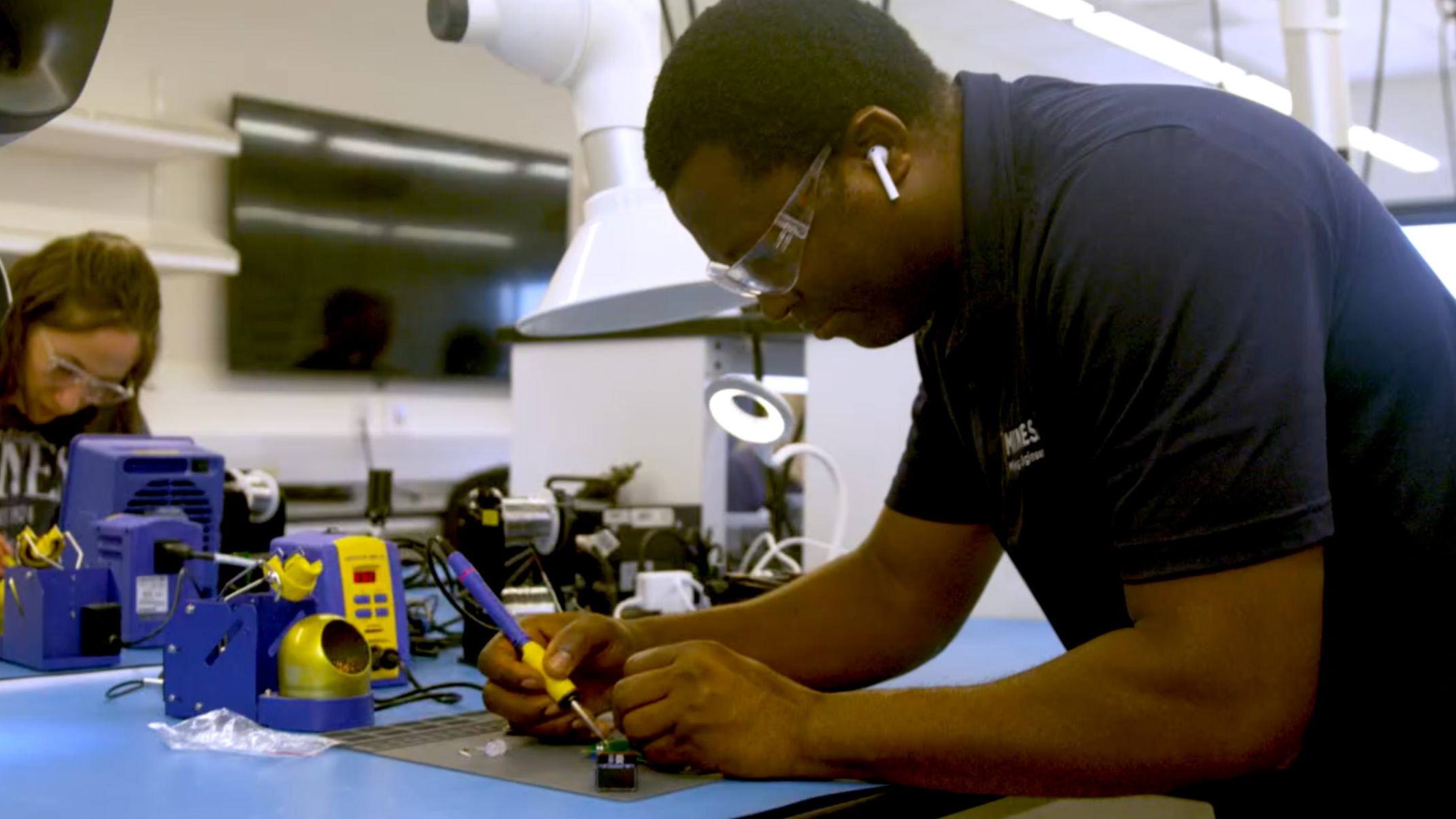 A man and a woman working on electronics in a lab.