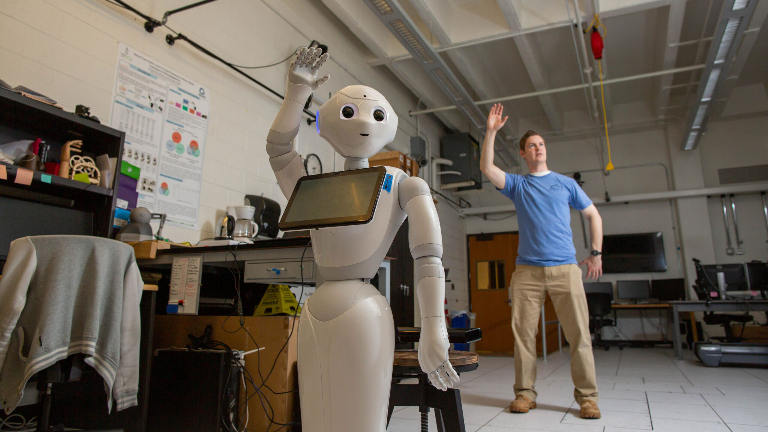 A man standing next to a robot in a room.
